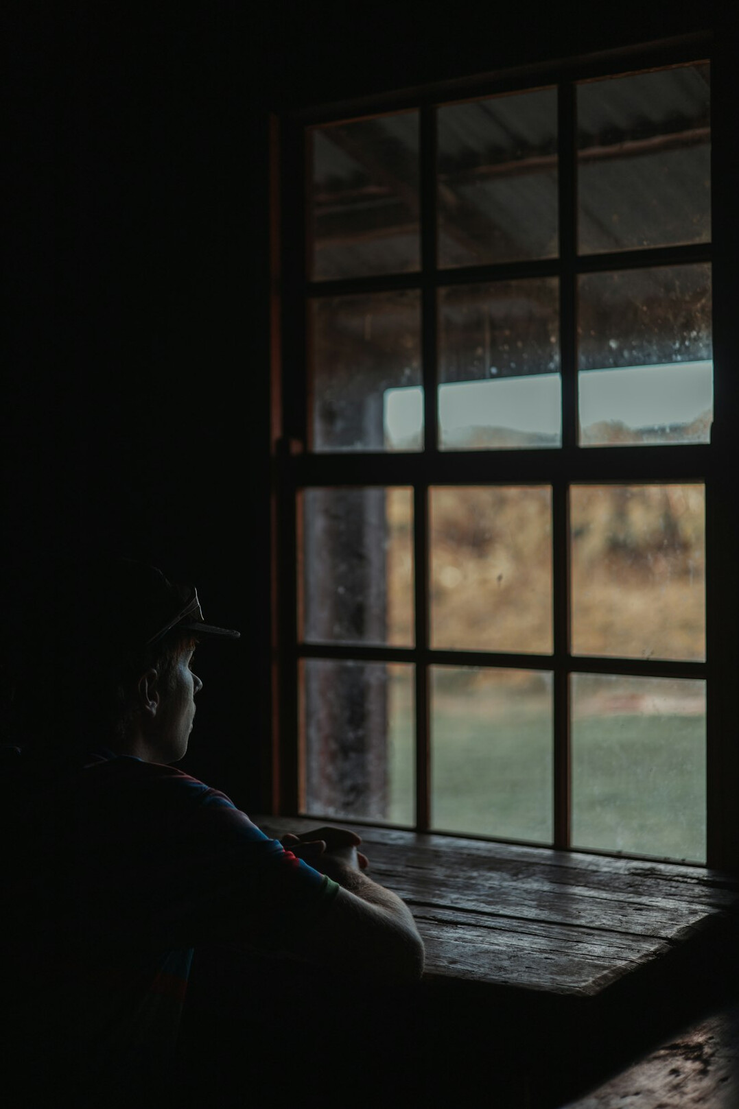 Person sitting quietly by a window in a reflective moment