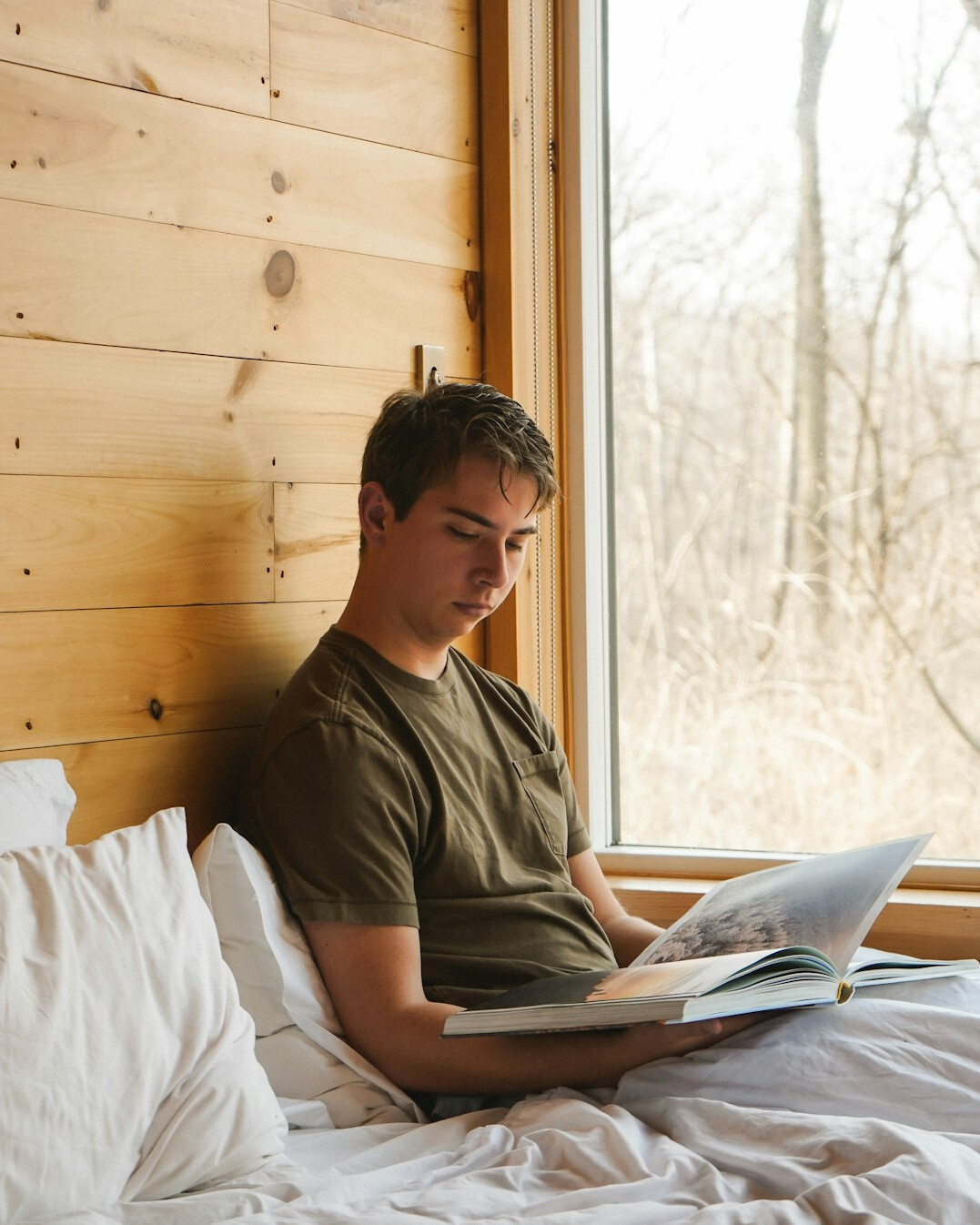 Brazilian man sitting calmly on a sofa reading by a window